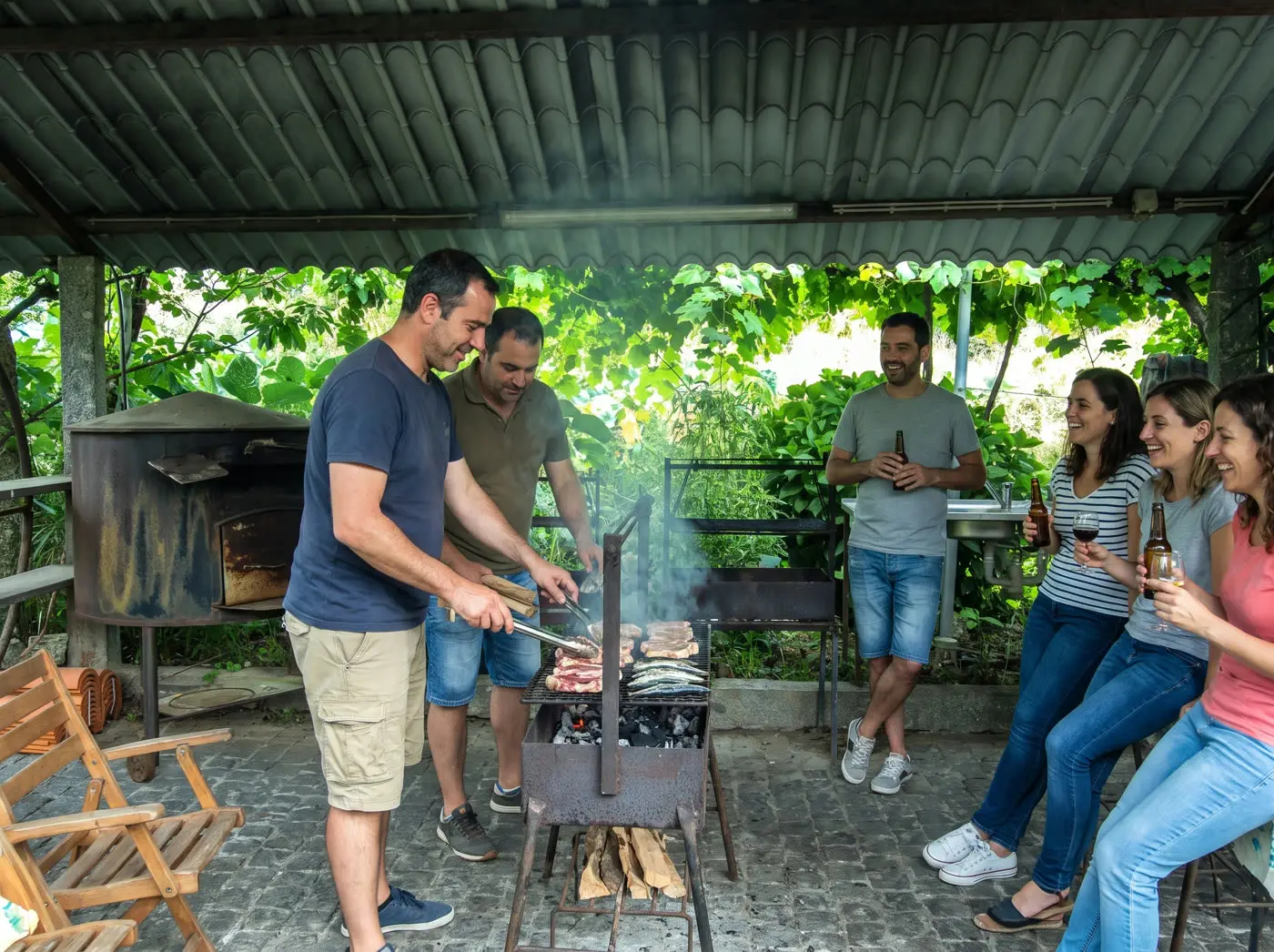 Amis préparant un barbecue dans l'espace grillades couvert du domaine